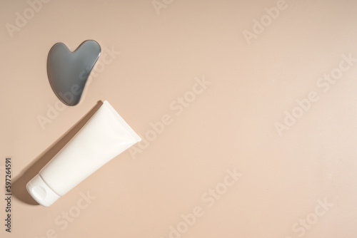 A face metal massager made of steal and a white tube of cream, product line presentation, marketing and branding