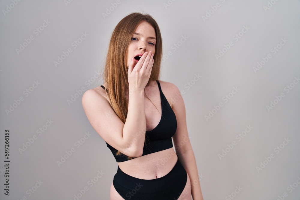 Young caucasian woman wearing lingerie bored yawning tired covering mouth with hand. restless and sleepiness. Young caucasian woman wearing lingerie bored yawning tired covering mouth with hand. restless and sleepiness.