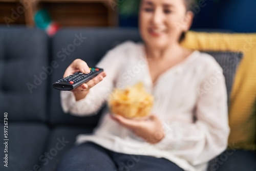 Middle age woman watching movie sitting on sofa at home