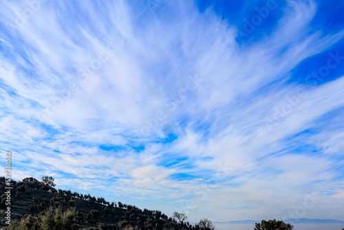 view of meadows and hills against the blue sky with clouds