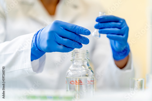 hands of scientists in blue rubber gloves examine chemical samples in laboratory