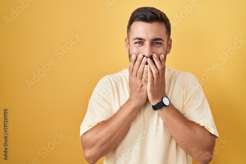 Принти на полотні Handsome hispanic man standing over yellow background laughing and embarrassed g
