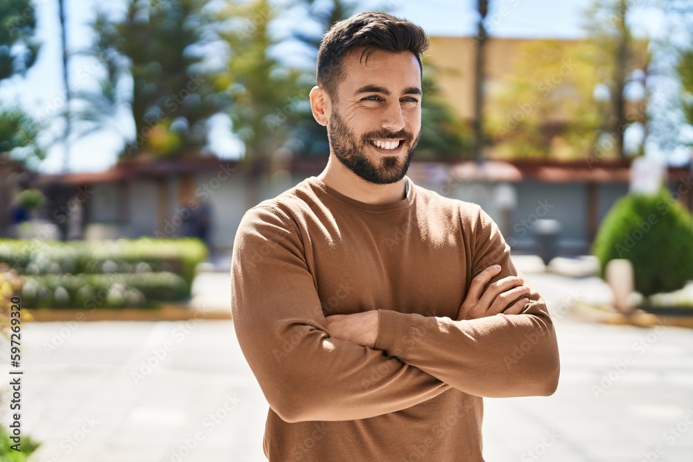 Young hispanic man smiling confident standing with arms crossed gesture at park