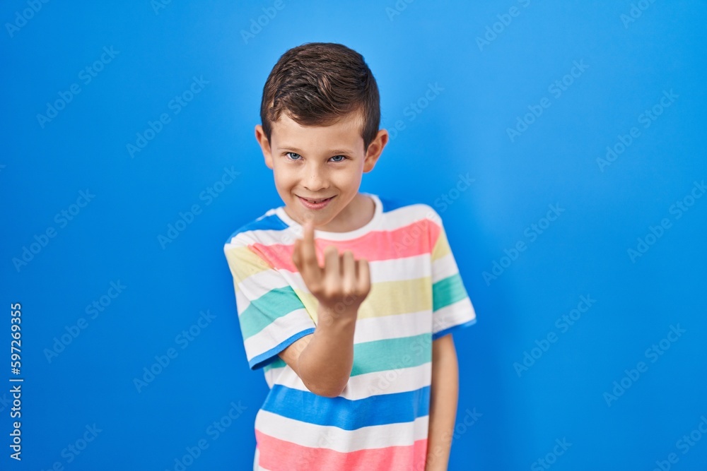 Young caucasian kid standing over blue background beckoning come here gesture with hand inviting welcoming happy and smiling Young caucasian kid standing over blue background beckoning come here gesture with hand inviting welcoming happy and smiling