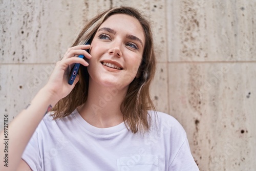 Young woman smiling confident talking on the smartphone at street