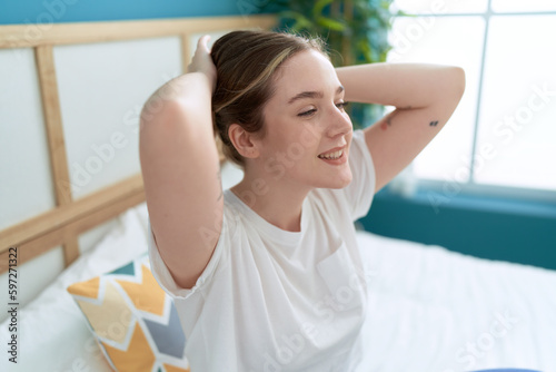 Young caucasian woman combing hair with hands sitting on bed at bedroom Free Download Young caucasian woman combing hair with hands sitting on bed at bedroom - GFXLoad