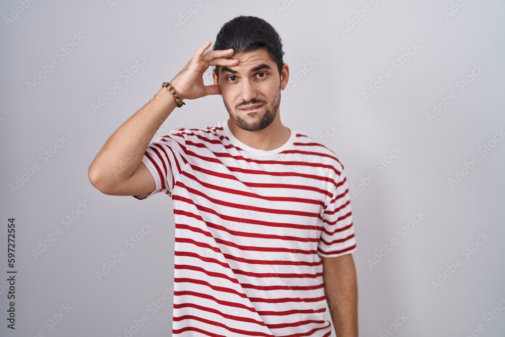 Fototapeta premium Hispanic man with long hair standing over isolated background worried and stressed about a problem with hand on forehead, nervous and anxious for crisis