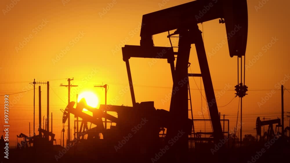 The sun rises behind oil pumps in California