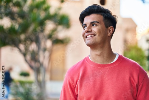 Young hispanic man smiling confident looking to the side at park