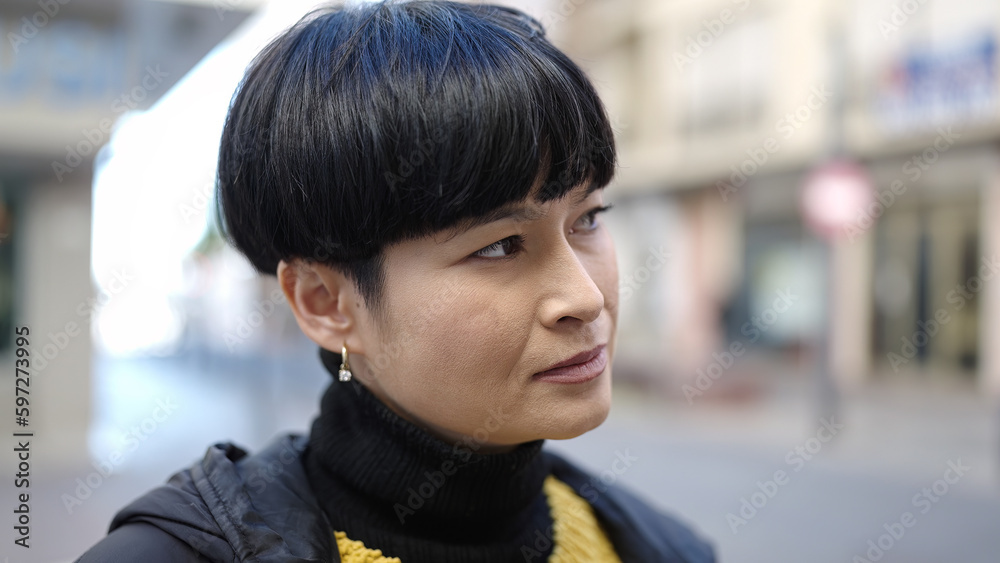 Young chinese woman looking to the side with serious expression at street Young chinese woman looking to the side with serious expression at street