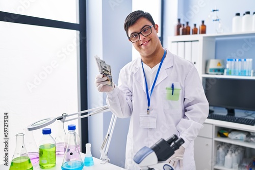 Down syndrome man wearing scientist uniform holding dollars at laboratory