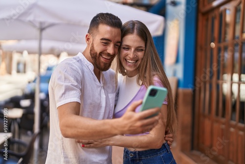 Man and woman couple smiling confident using smartphone at street