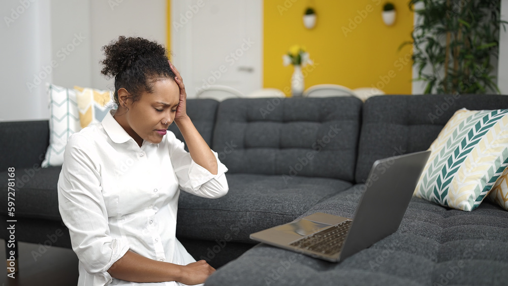 African american woman using laptop with stressed expression at home