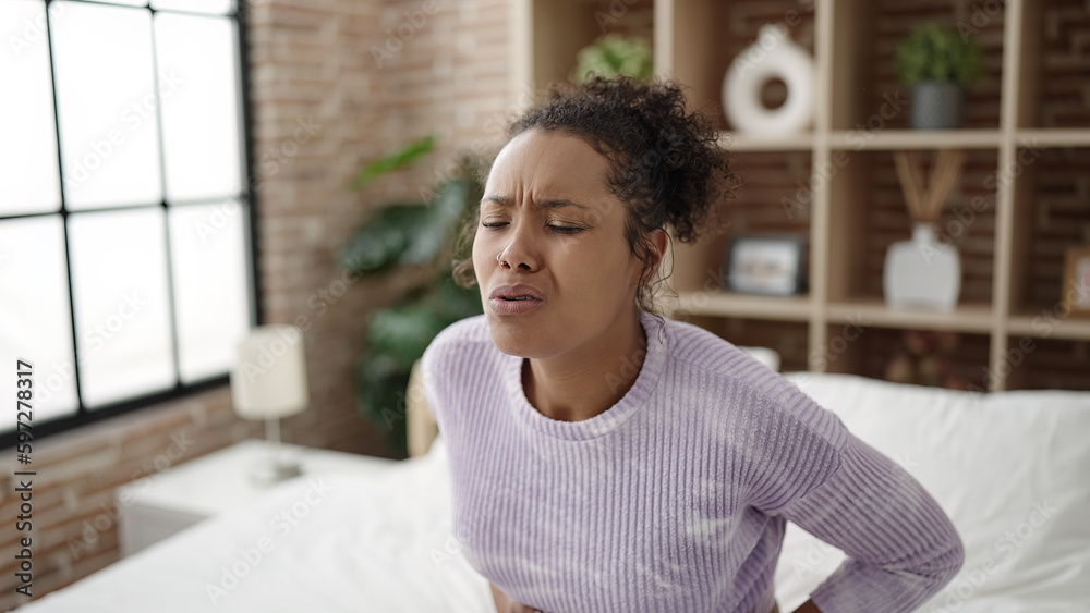 African american woman suffering for stomach ache sitting on bed at bedroom African american woman suffering for stomach ache sitting on bed at bedroom