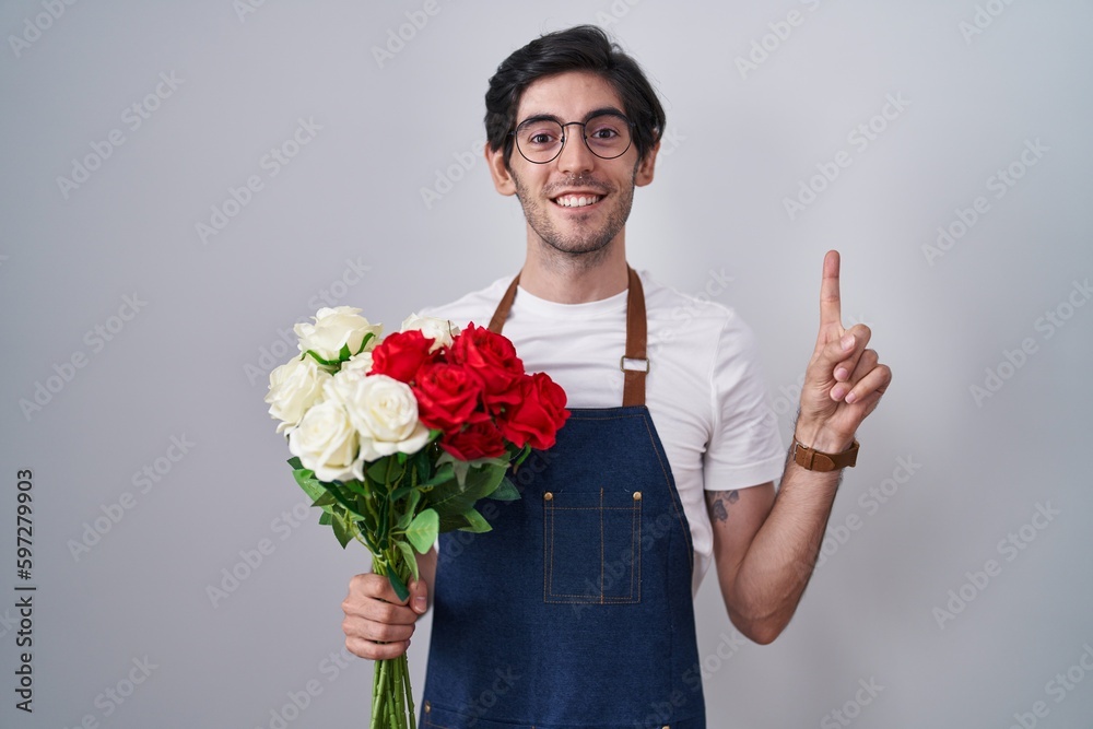 Young hispanic man holding bouquet of white and red roses smiling amazed and surprised and pointing up with fingers and raised arms. Young hispanic man holding bouquet of white and red roses smiling amazed and surprised and pointing up with fingers and raised arms.