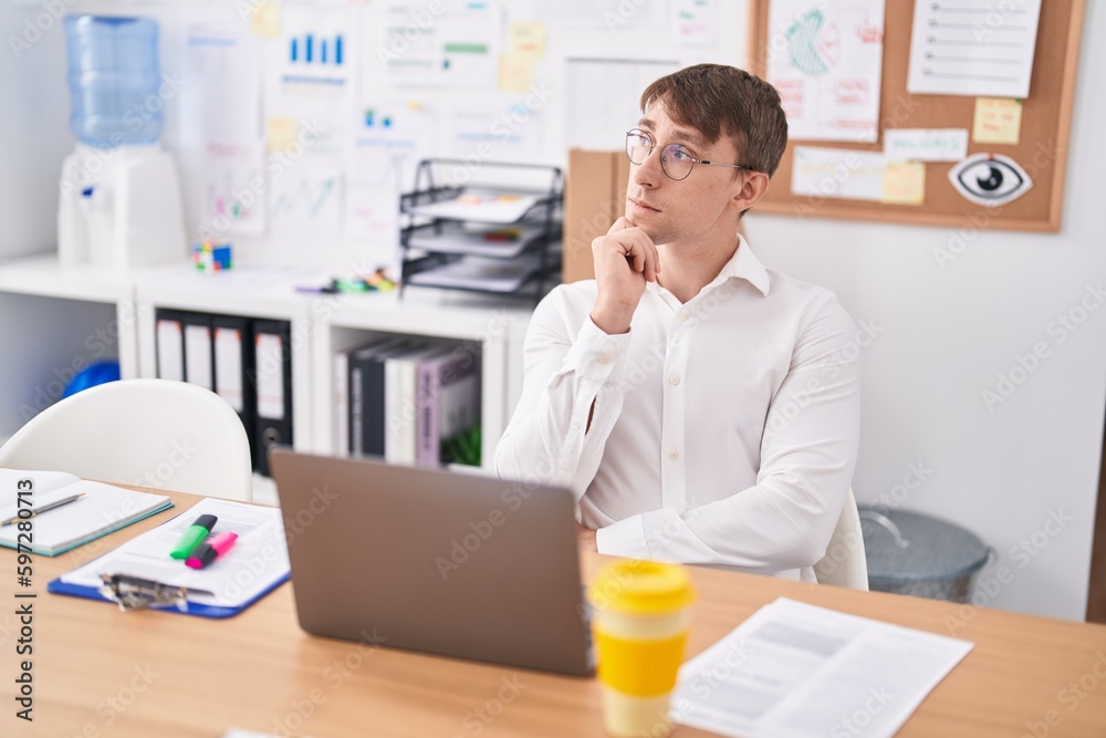 Young caucasian man business worker using laptop with doubt expression at office Young caucasian man business worker using laptop with doubt expression at office