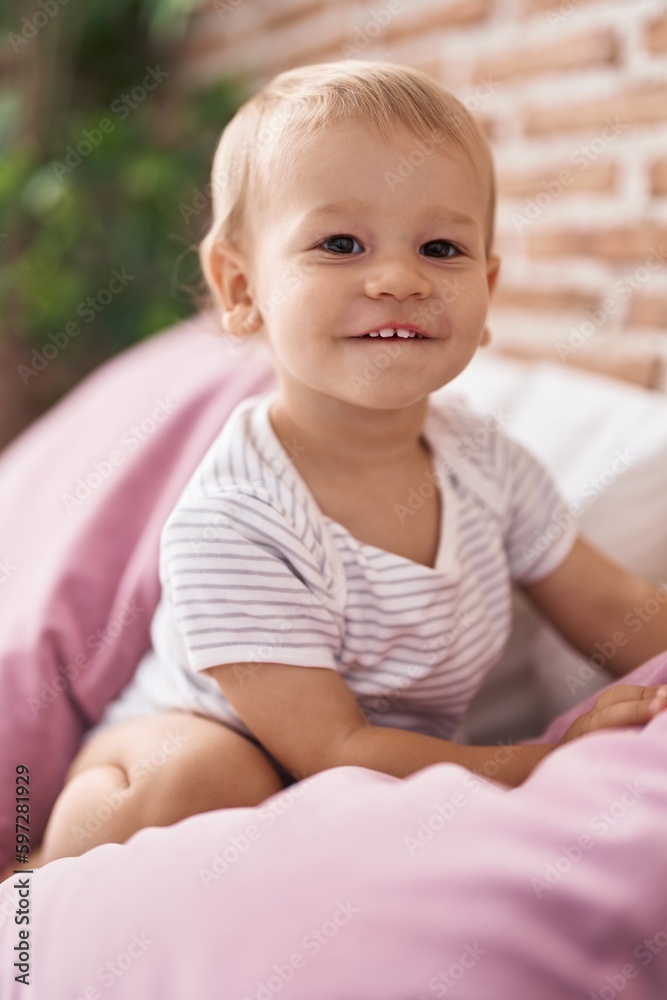 Adorable toddler smiling confident sitting on bed at bedroom Adorable toddler smiling confident sitting on bed at bedroom