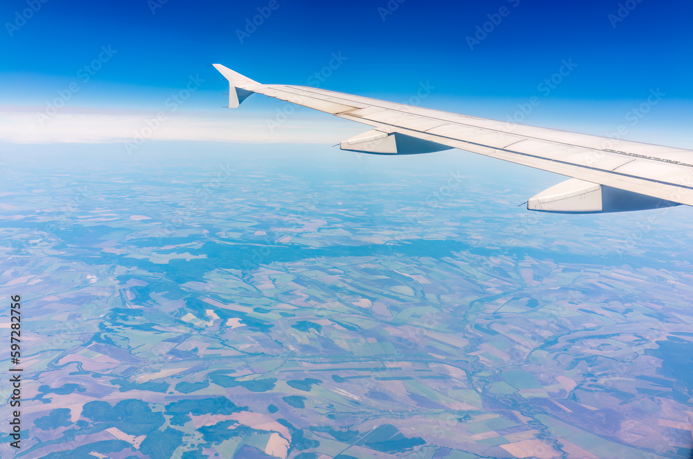 Aerial view from airplane window above green ground. View from the airplane window with beautiful clouds at sunrise Aerial view from airplane window above green ground. View from the airplane window with beautiful clouds at sunrise