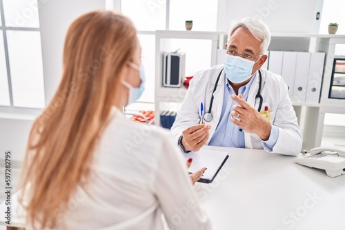 Middle age man and woman doctor and patient wearing medical mask having consultation at clinic © Krakenimages.com