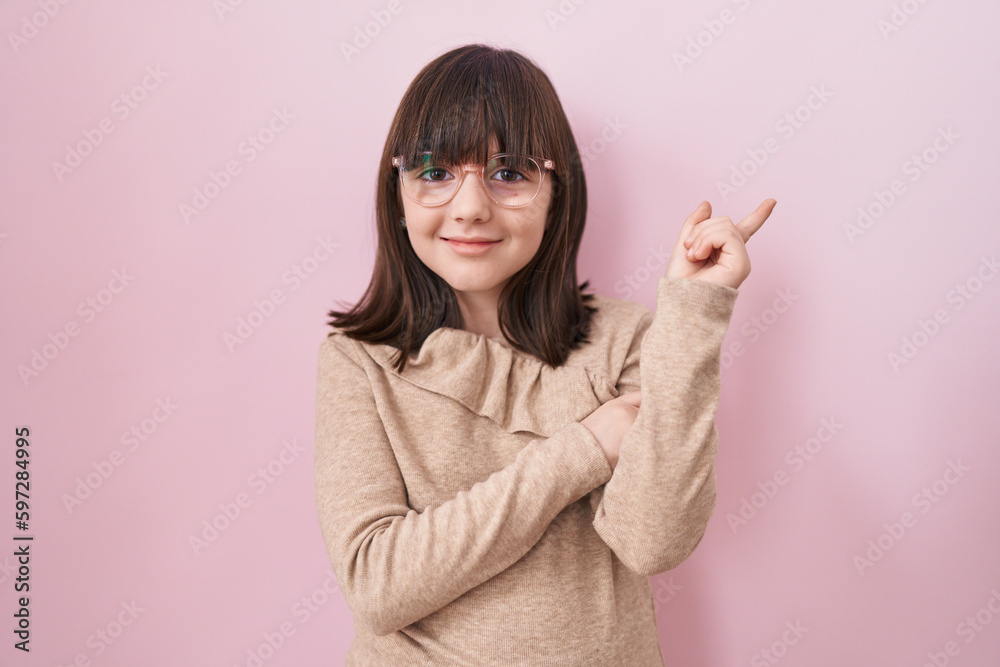 Little hispanic girl wearing glasses smiling happy pointing with hand and finger to the side Little hispanic girl wearing glasses smiling happy pointing with hand and finger to the side