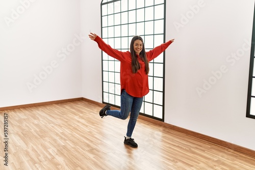 Young latin woman smiling confident dancing at empty room