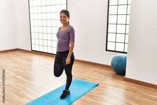 Young latin woman smiling confident stretching at sport center