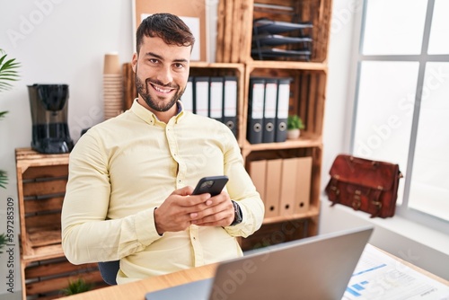 Young hispanic man business worker using smartphone working at office