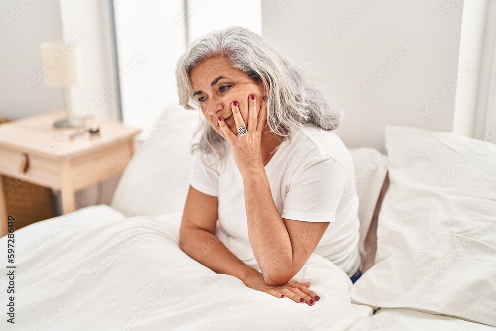 Middle age woman stressed sitting on bed at bedroom Middle age woman stressed sitting on bed at bedroom