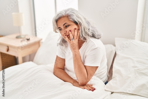 Middle age woman stressed sitting on bed at bedroom