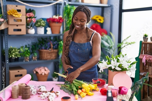 African american woman florist cutting stem at flower shop