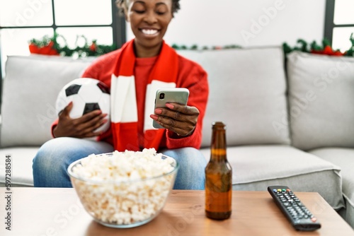 African american woman supporting soccer team using smartphone at home © Krakenimages.com