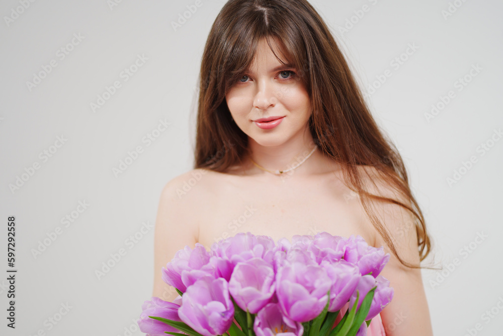 portrait of a woman topless with a bouquet of tulips on a white background.