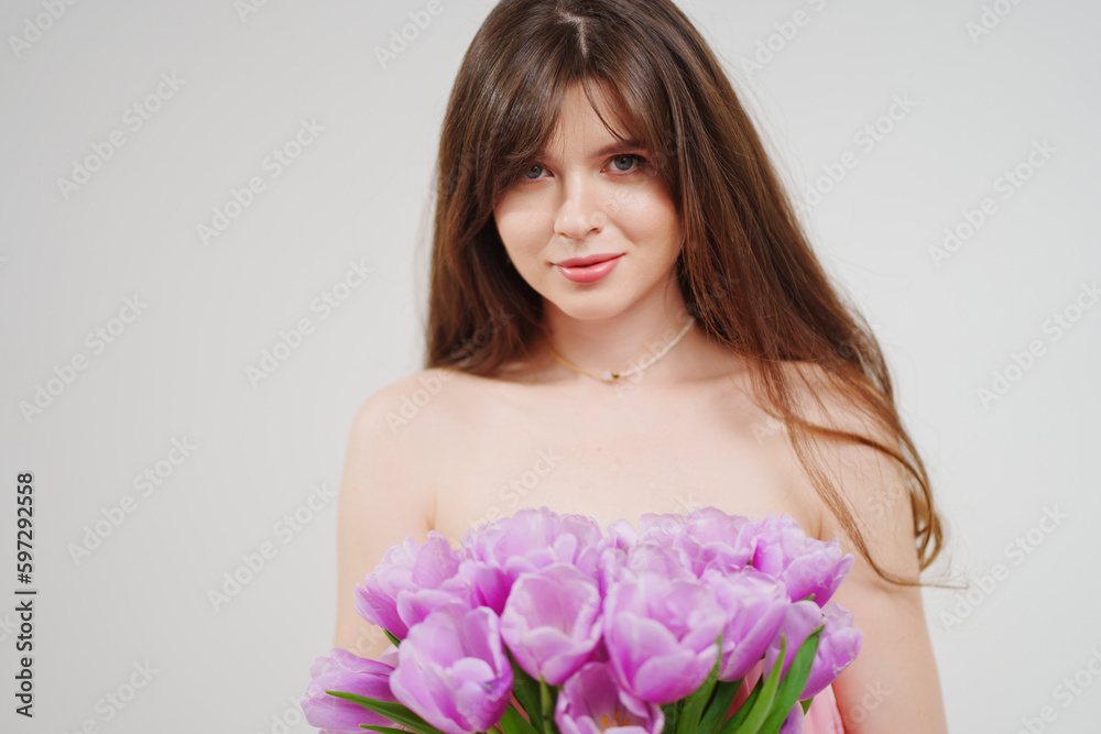 portrait of a woman topless with a bouquet of tulips on a white background. portrait of a woman topless with a bouquet of tulips on a white background.