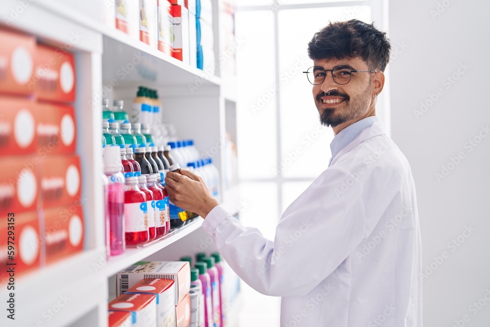 Young hispanic man pharmacist organize shelving at pharmacy