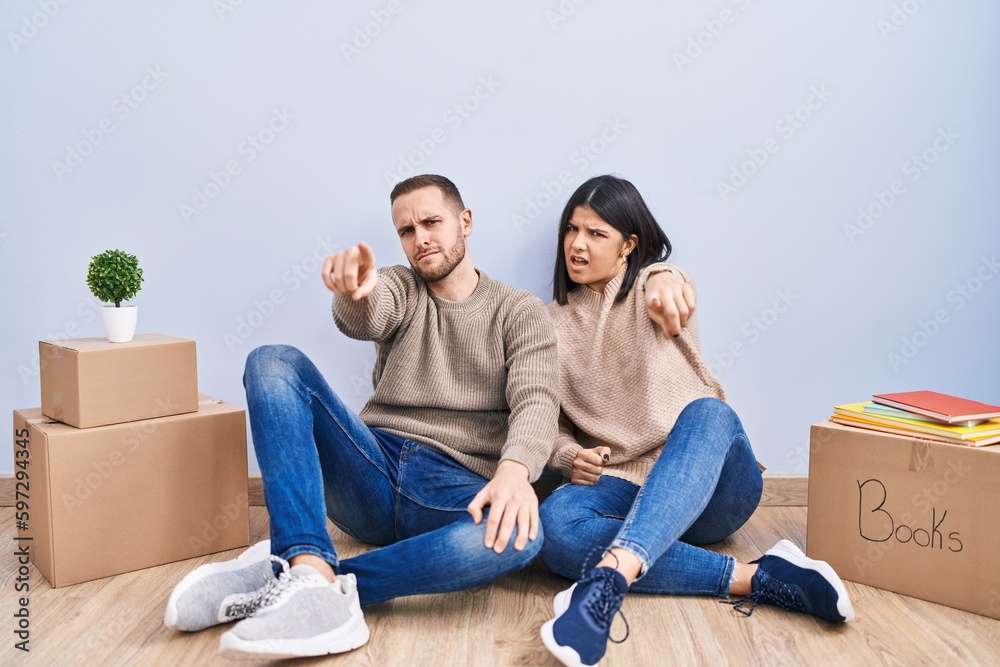 Young couple moving to a new home pointing displeased and frustrated to the camera, angry and furious with you Young couple moving to a new home pointing displeased and frustrated to the camera, angry and furious with you