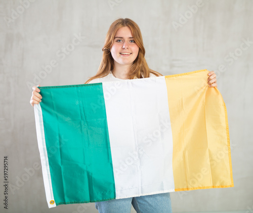 Pretty young female student holding the Ireland flag in her hands