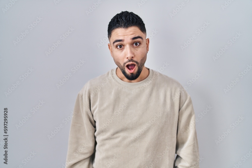 Fototapeta premium Young handsome man standing over isolated background in shock face, looking skeptical and sarcastic, surprised with open mouth