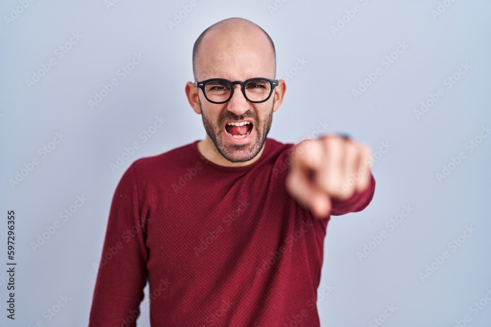 Naklejka premium Young bald man with beard standing over white background wearing glasses pointing displeased and frustrated to the camera, angry and furious with you