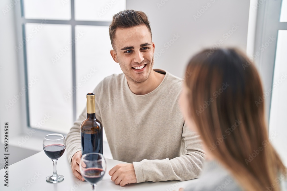 Man and woman couple drinking red wine sitting on table at home Man and woman couple drinking red wine sitting on table at home