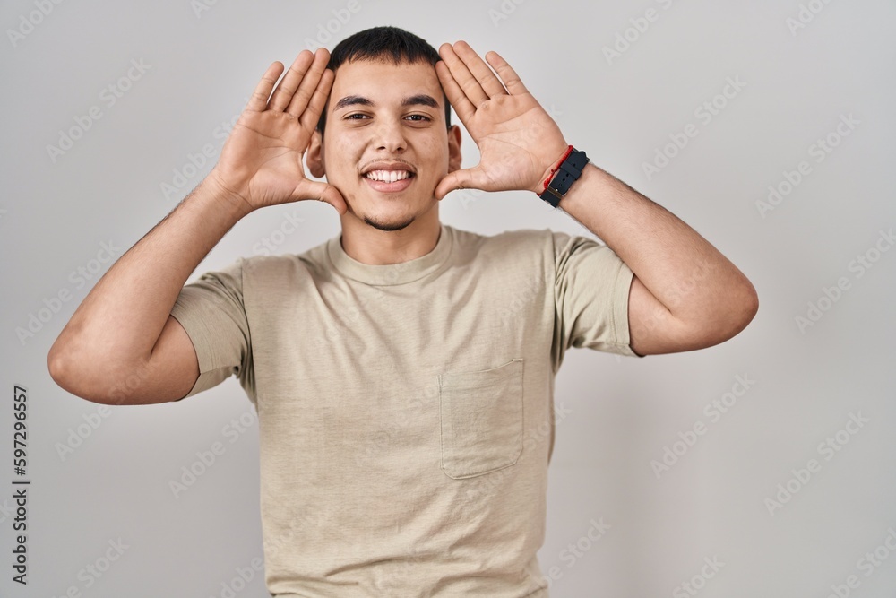 Young arab man wearing casual t shirt smiling cheerful playing peek a boo with hands showing face. surprised and exited Young arab man wearing casual t shirt smiling cheerful playing peek a boo with hands showing face. surprised and exited