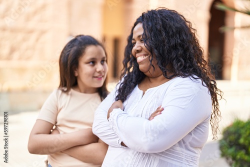 Mother and daughter smiling confident standing with arms crossed gesture at street
