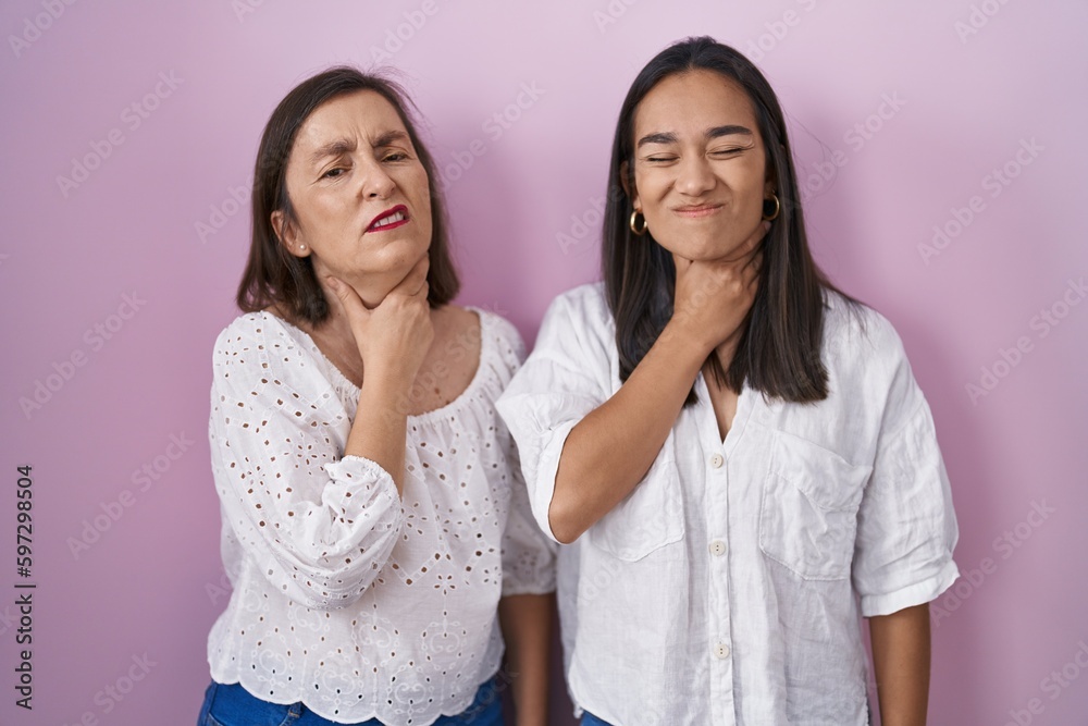 Hispanic mother and daughter together touching painful neck, sore throat for flu, clod and infection Hispanic mother and daughter together touching painful neck, sore throat for flu, clod and infection