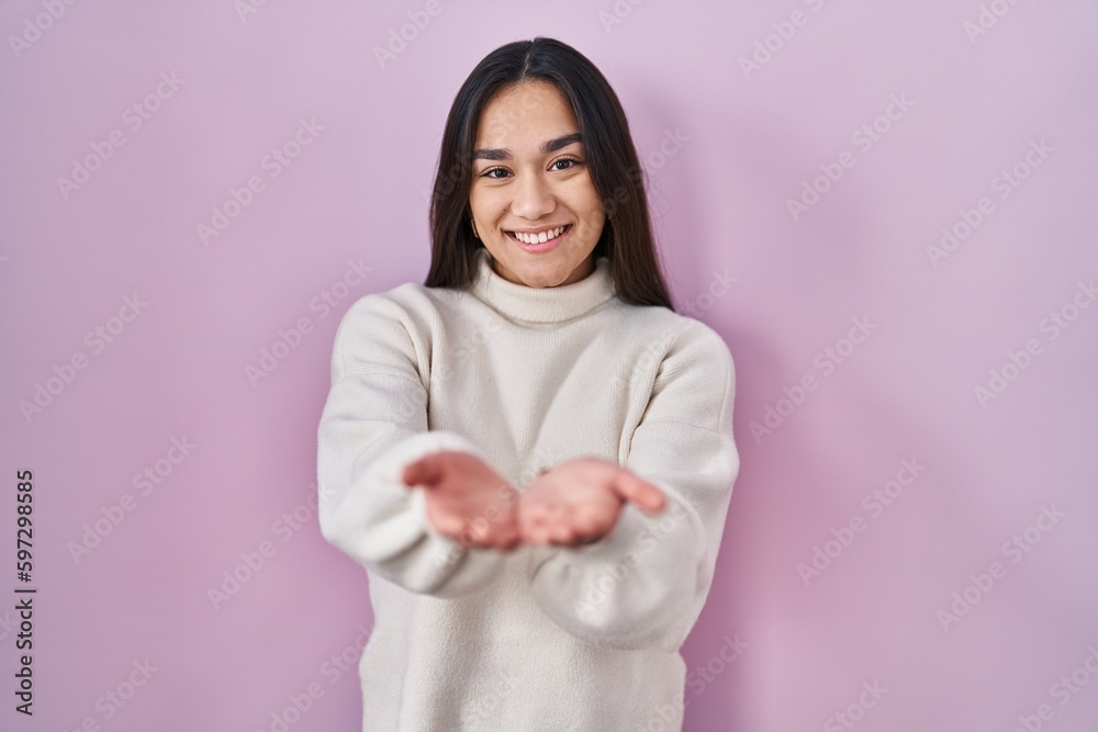 Young south asian woman standing over pink background smiling with hands palms together receiving or giving gesture. hold and protection Young south asian woman standing over pink background smiling with hands palms together receiving or giving gesture. hold and protection