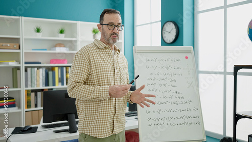 Middle age man teacher teaching maths lesson at classroom