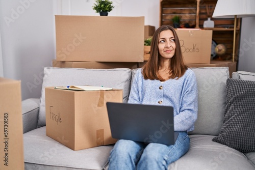 Young woman using laptop sitting on sofa at new home