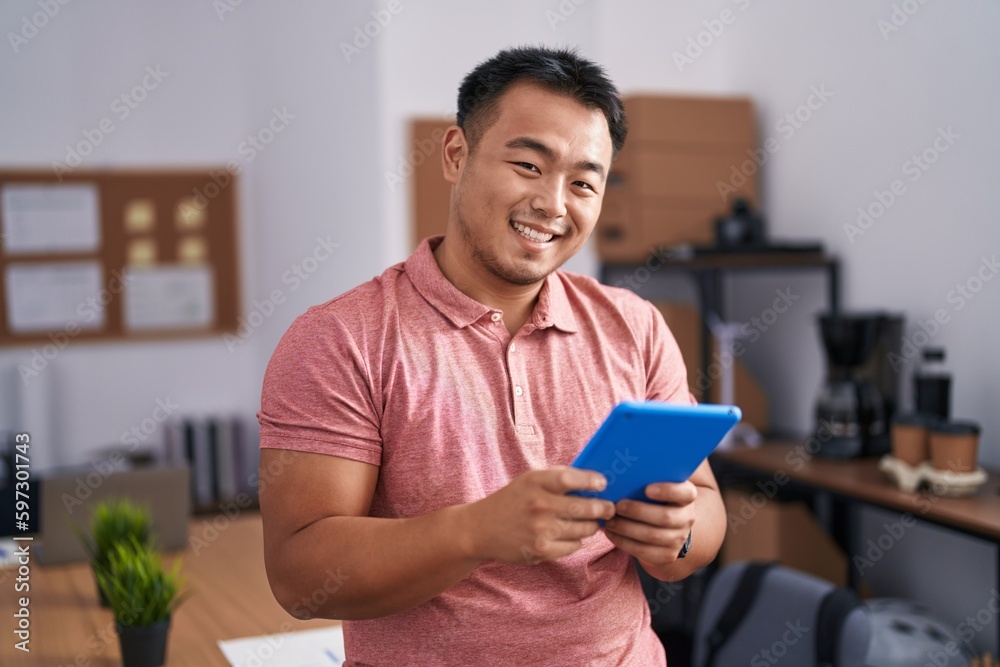 Young chinese man business worker smiling confident using touchpad at office