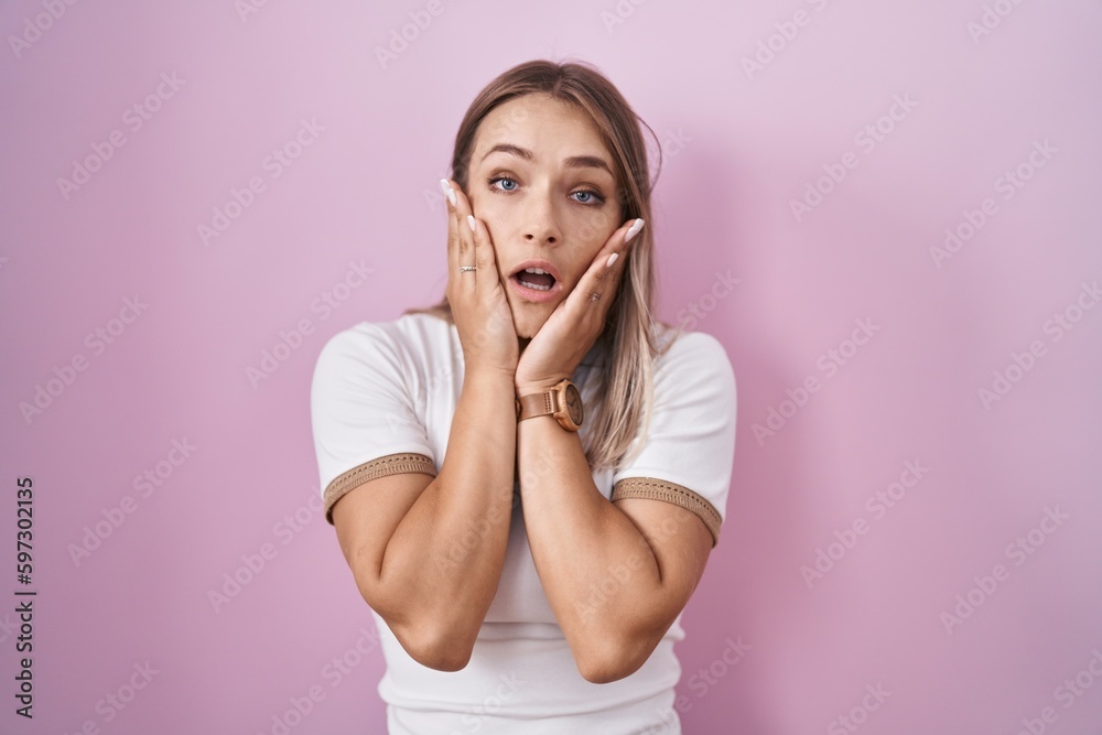 Blonde caucasian woman standing over pink background tired hands covering face, depression and sadness, upset and irritated for problem
