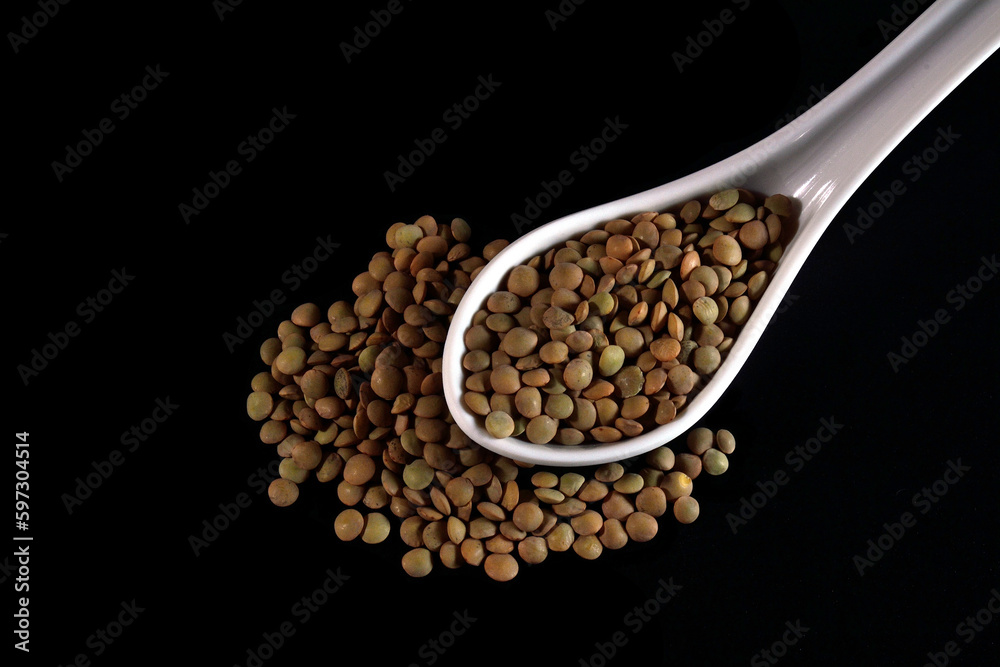 White ceramic spoon full of lentils, isolated on black background. White ceramic spoon full of lentils, isolated on black background.