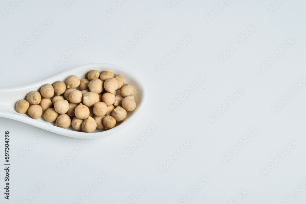 White ceramic spoon full of chickpeas on white background. White ceramic spoon full of chickpeas on white background.