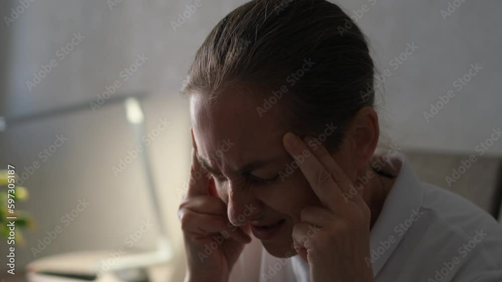 Adult 50 year old woman with headache massages her temples, close-up Adult 50 year old woman with headache massages her temples, close-up